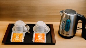 A tray with two white cups, two packets of tea, and a stainless steel electric kettle on a wooden surface. - L Meridian Suites (Zamboanga)