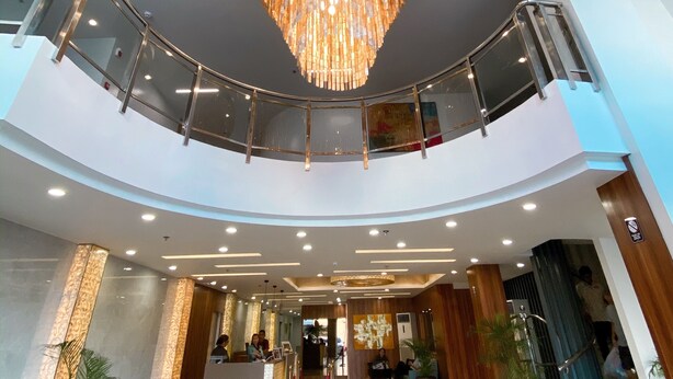 A spacious lobby with a grand chandelier, a reception desk, and a curved glass railing overlooking the lower level. - L Meridian Suites (Zamboanga)