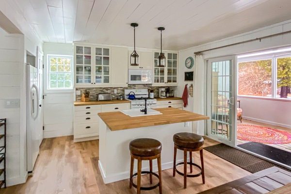 The full kitchen leads directly onto the screened-in porch. Kitchen Island from the dining table hand made by our neighbor, a talented woodworker. All the cooking space, utensils, cookware, and everything else you need, right there.