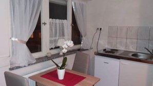A small kitchen with a dining table, a potted plant, and a window with curtains. - Apartments B & B27 (Rottweil)