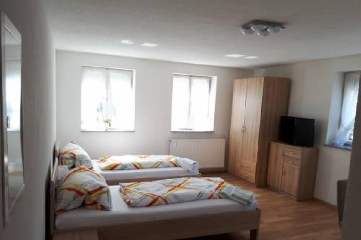 A bedroom with two beds, a wooden wardrobe, and a television.