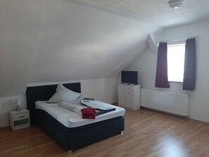 A bedroom with a bed, a nightstand, a dresser, a window with curtains, and a ceiling light. - Apartments B & B27 (Rottweil)