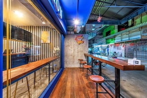 A bar area with wooden stools, a counter, and a neon sign.