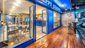 Um restaurante com fachada azul e um letreiro que diz 'HAPPY STATION'.