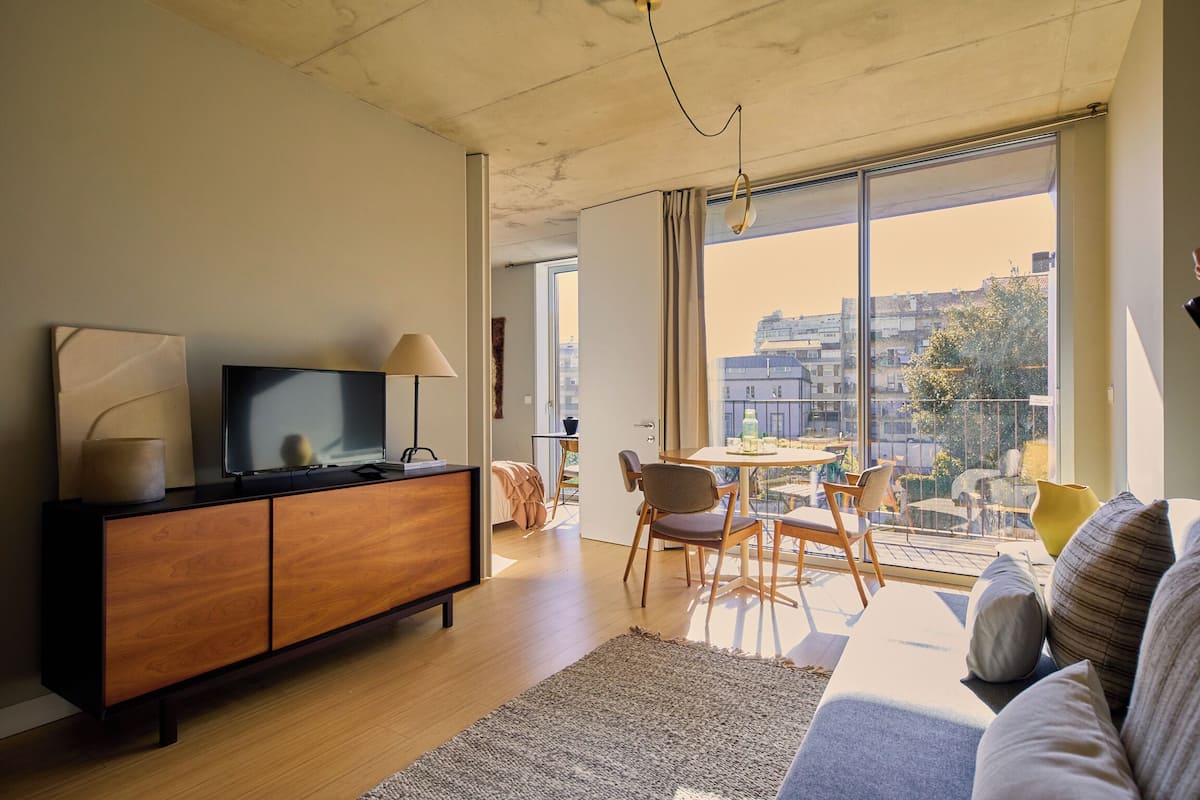 Una sala moderna con un mueble de madera, un televisor de pantalla plana, un sofá y un comedor con sillas y una mesa.