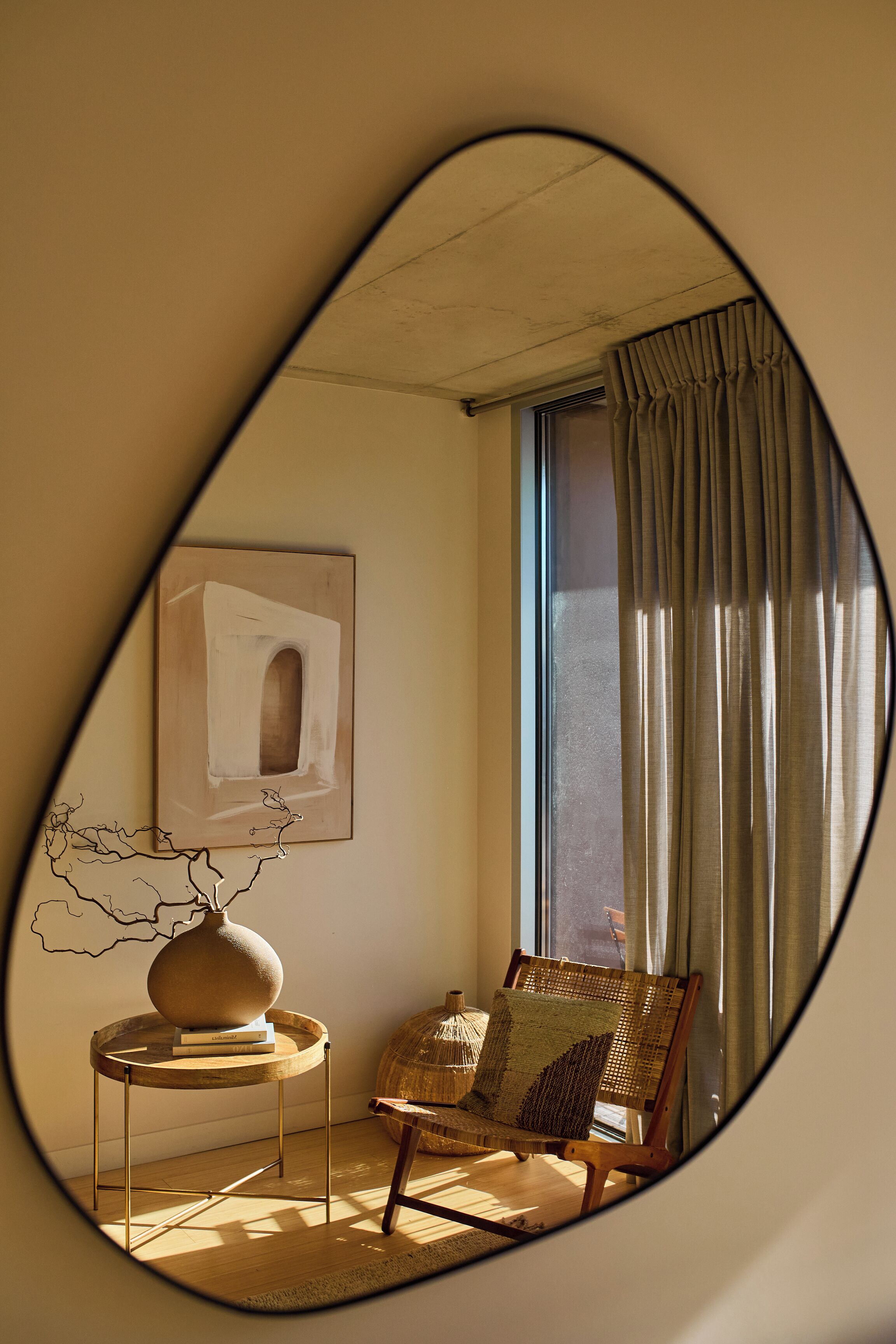 A room with a round table, a chair, a vase, and a framed picture on the wall.