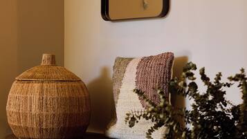 A wooden bench with a woven basket and a textured cushion against a wall.
