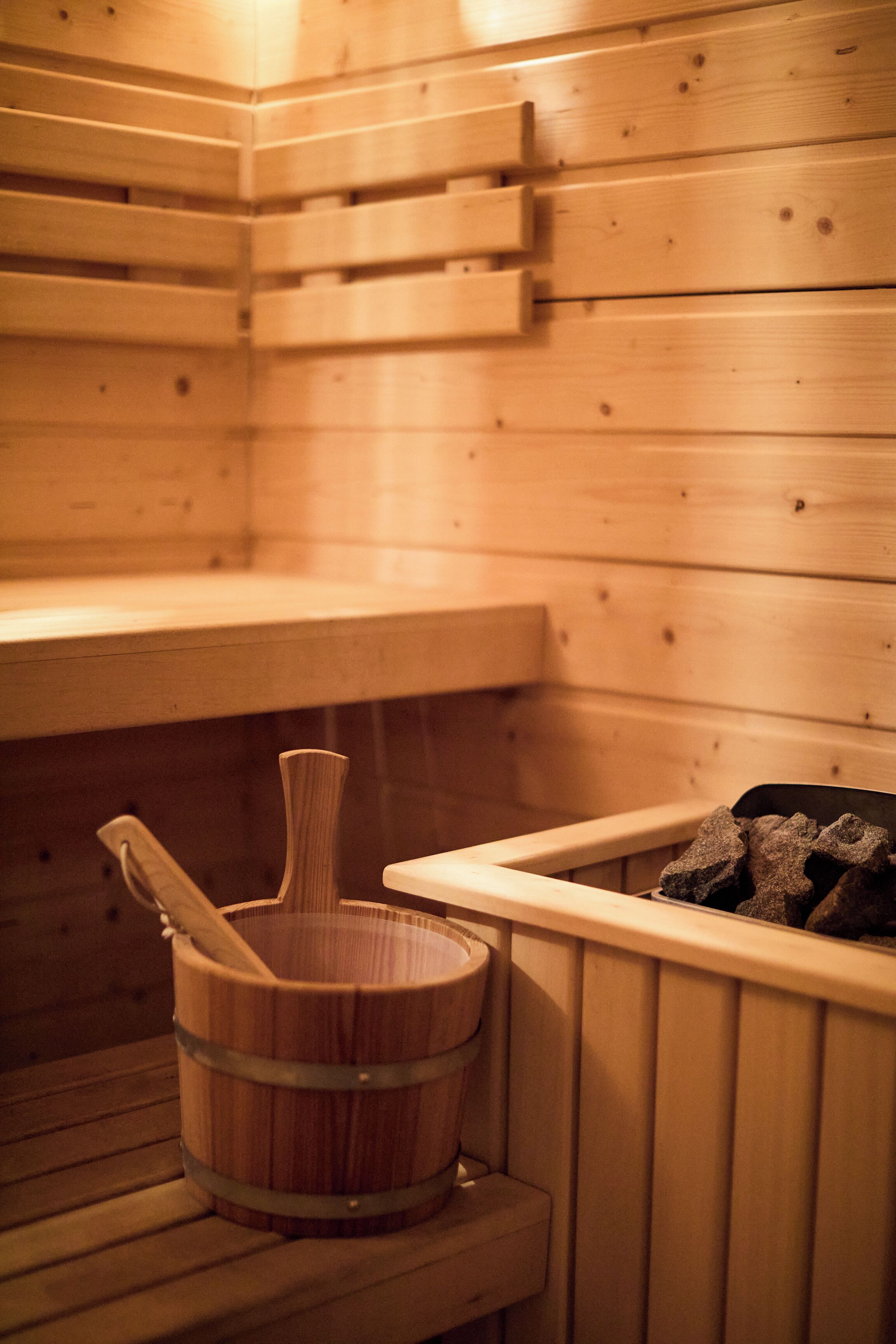 Una sauna de madera con bancos y un balde de madera.