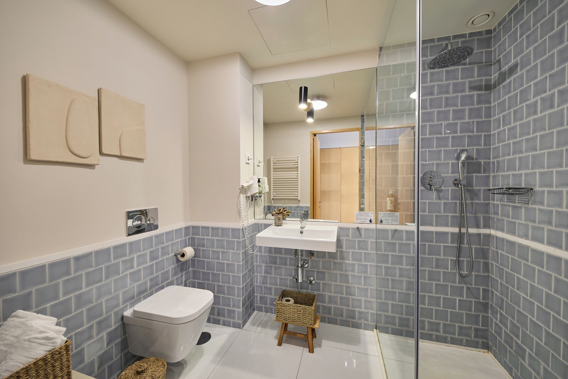 A modern bathroom with a glass-enclosed shower, a white sink, and a toilet.