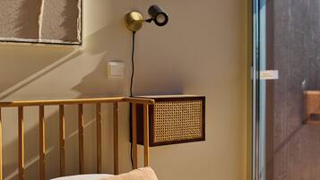 Een slaapkamer met een houten hoofdbord, een bed met beige beddengoed, een wandlamp en een raam met uitzicht.