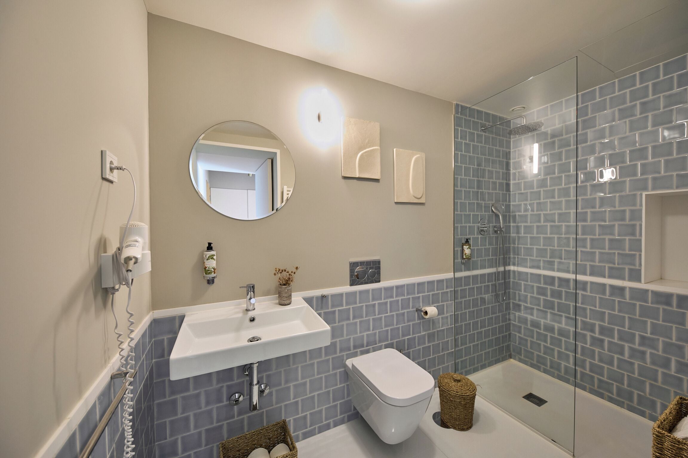 Une salle de bain avec un lavabo blanc, des toilettes, une douche en verre et un miroir.