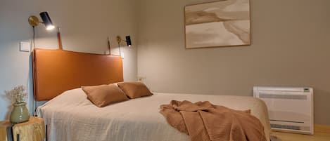 Una camera da letto con un letto, lampade sui comodini, un condizionatore d'aria a parete e un quadro.
