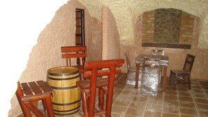 Una habitación rústica con pared de piedra, muebles de madera y suelo de baldosas.