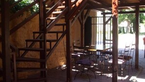 Una escalera de madera que conduce a un espacio al aire libre cubierto con una mesa y sillas.
