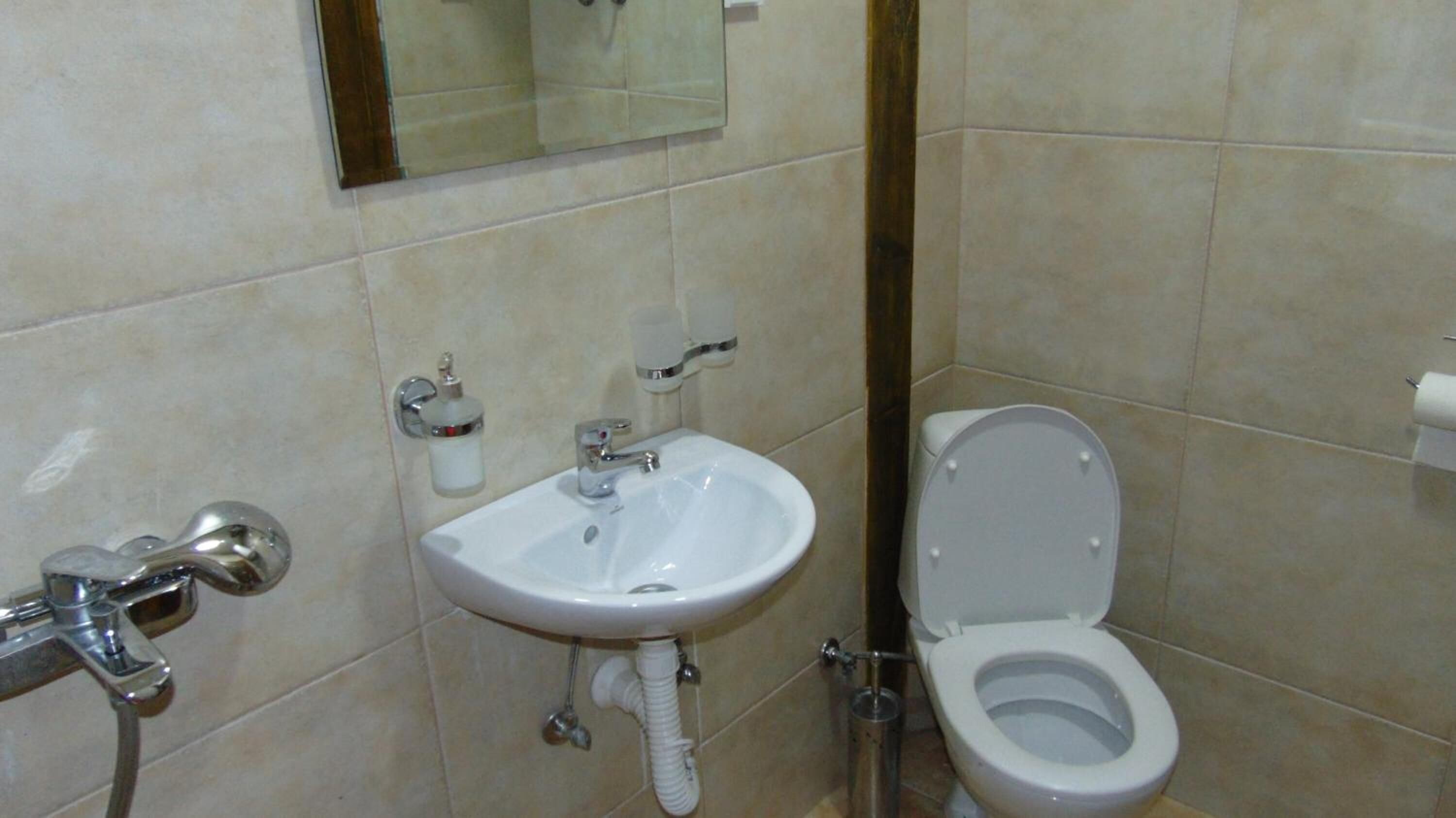 A bathroom with a white sink, a toilet, and a mirror on the wall.