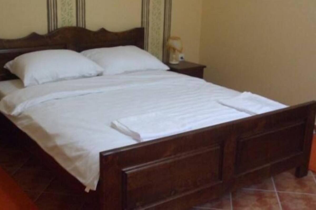 A neatly made bed with white linens in a room with a wooden headboard and two bedside tables.