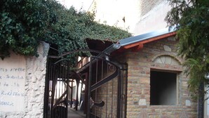 Una reja de hierro forjado que da paso a un edificio de fachada de ladrillo y una ventana pequeña.