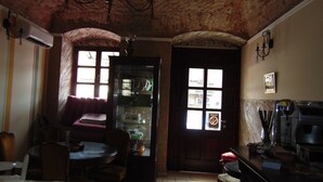 Una habitación con techo de ladrillo, una mesa de comedor con sillas, un sofá y una puerta con ventanas.