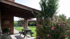 Un patio cubierto con un arco de ladrillo, una pérgola de madera y una mesa de picnic con sillas.