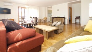 A spacious living room with a sofa, armchair, and a dining area with chairs and a table. - Apartment 1624/16704 (Istria - Novigrad), 600m from the beach (Novigrad)