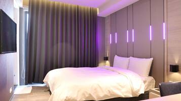 Una habitación de hotel moderna con una cama grande, un televisor de pantalla plana e iluminación ambiental.