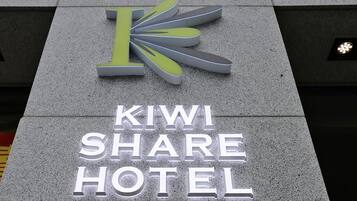 Señal del Kiwi Share Hotel, con una 'K' estilizada y el nombre del hotel en letras blancas grandes.