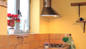 A kitchen with a stone countertop, a gas stove, and a stainless steel range hood.