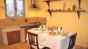 A kitchen with a dining table set for breakfast, including plates of food, cups, and a fruit bowl.