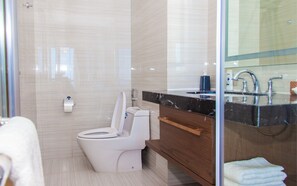 A modern bathroom with a toilet, bidet, vanity with a mirror, and a towel rack.