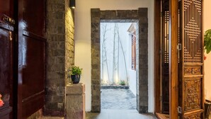 A stone archway leading to a courtyard with a view of a traditional building.