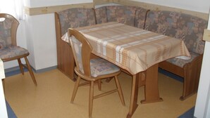 Un coin repas avec une table et deux chaises, un canapé à motifs et un mur uni.