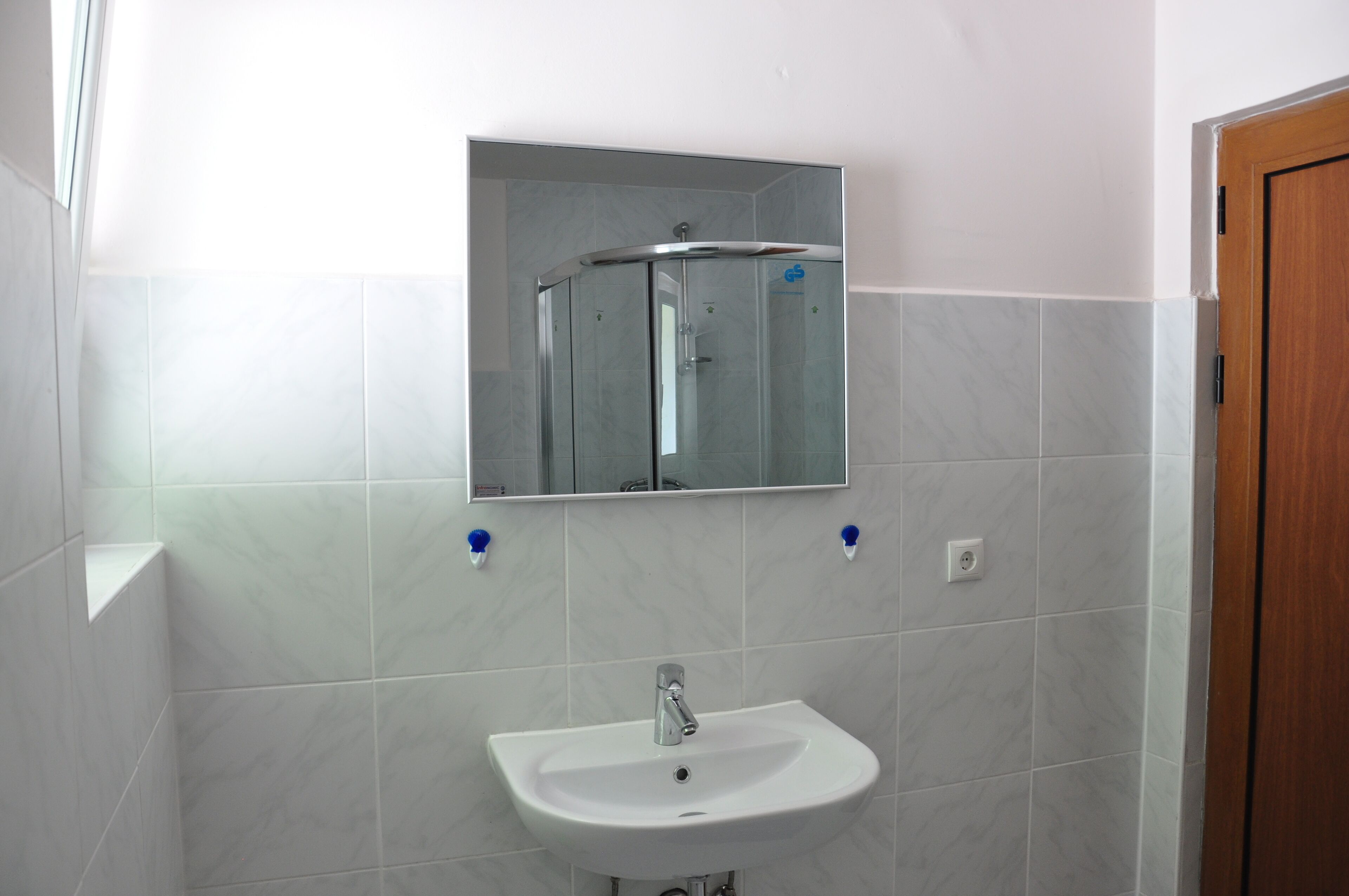 A bathroom with a white sink, a glass shower enclosure, and a mirror above the sink.