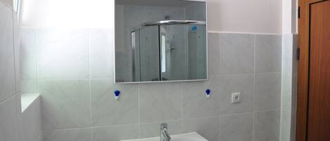A bathroom with a white sink, a glass shower enclosure, and a mirror above the sink.