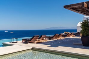 A poolside area with lounge chairs and a view of the sea. - Kalesma Mykonos (Mykonos)