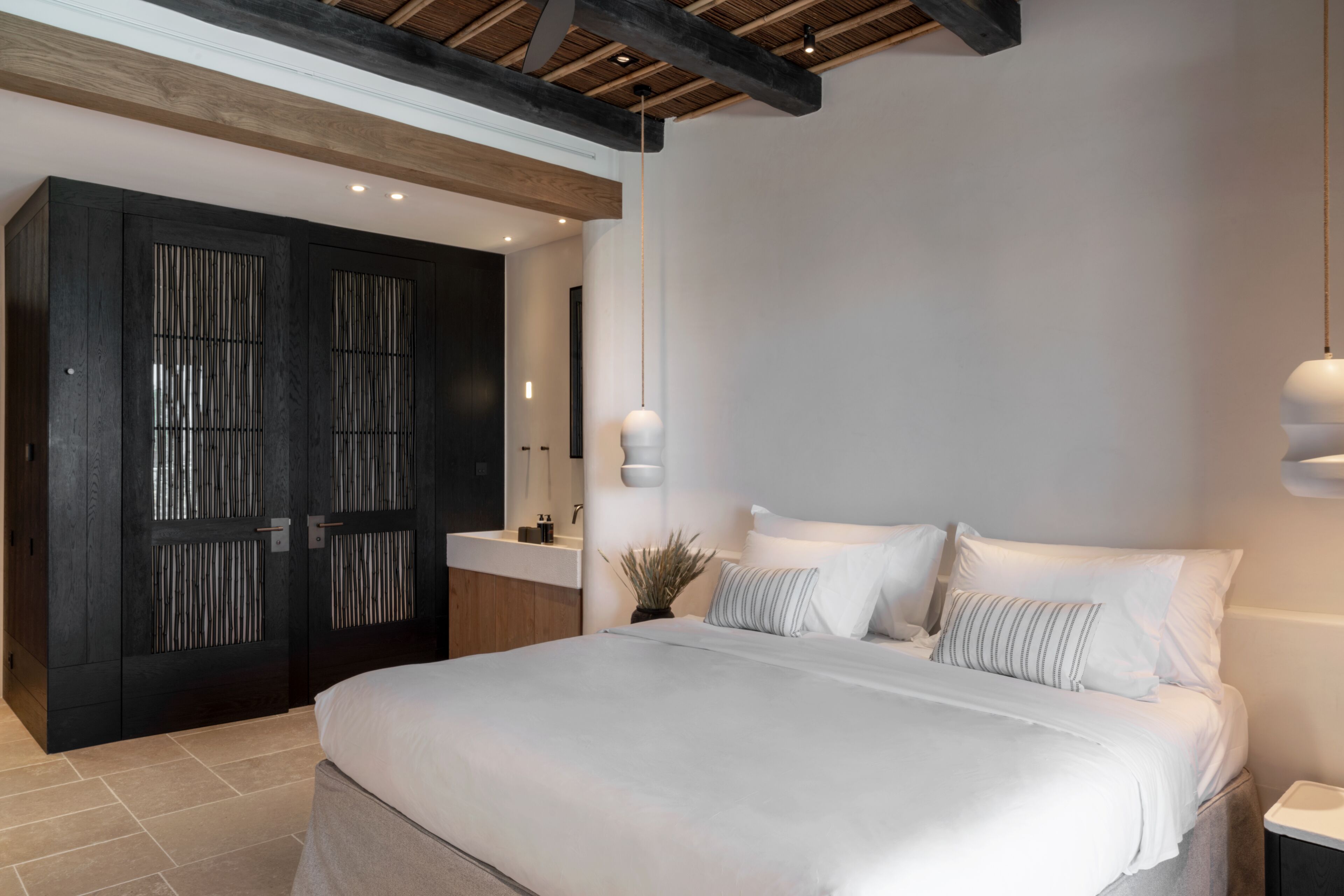 A modern bedroom with a large bed, a dark wooden wardrobe, and a minimalist design.