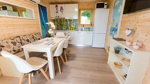 Een kleine keuken met witte kastjes, een magnetron en een koelkast.