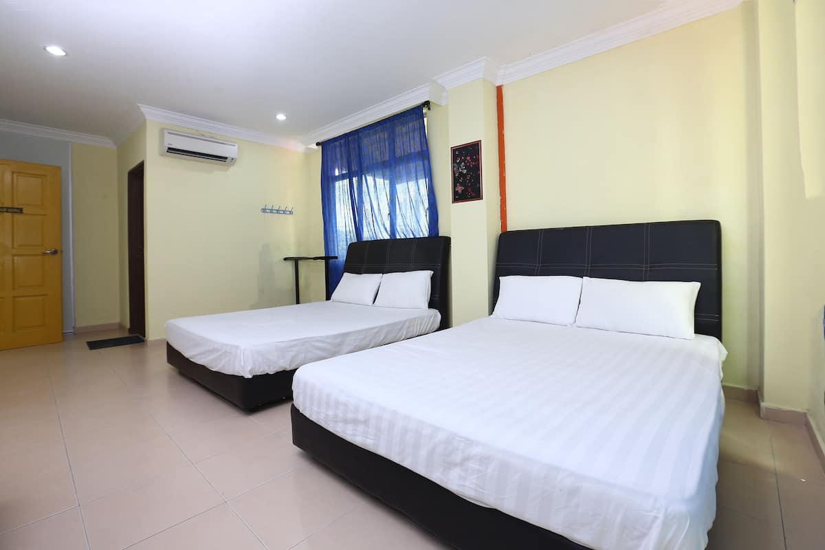 A hotel room with two beds, a door, an air conditioning unit, and a window with blue curtains.