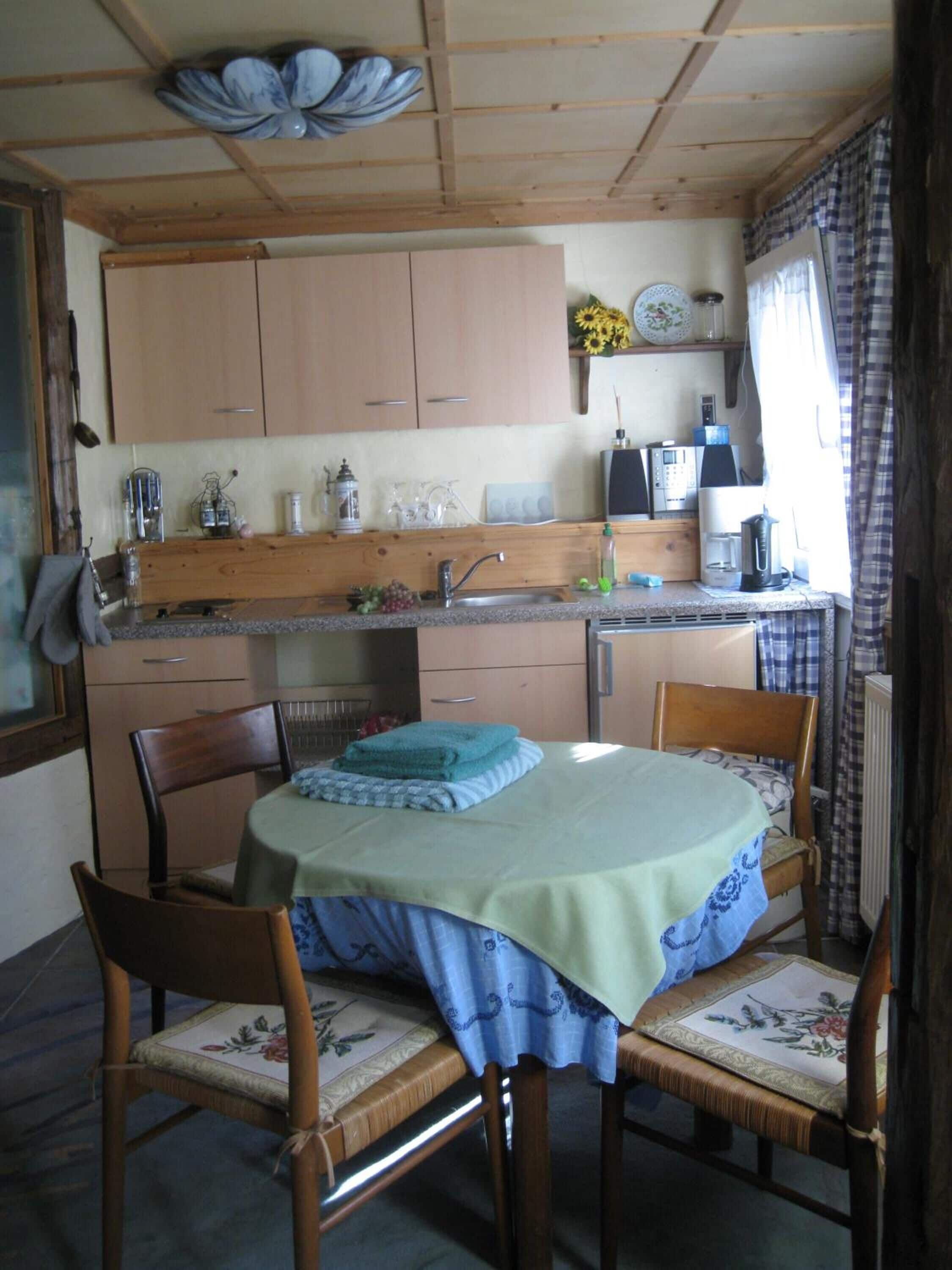Una cocina compacta con armarios de madera, un lavamanos y un comedor con mesa y sillas.
