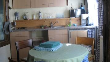 Una cocina compacta con armarios de madera, un lavamanos y un comedor con mesa y sillas.