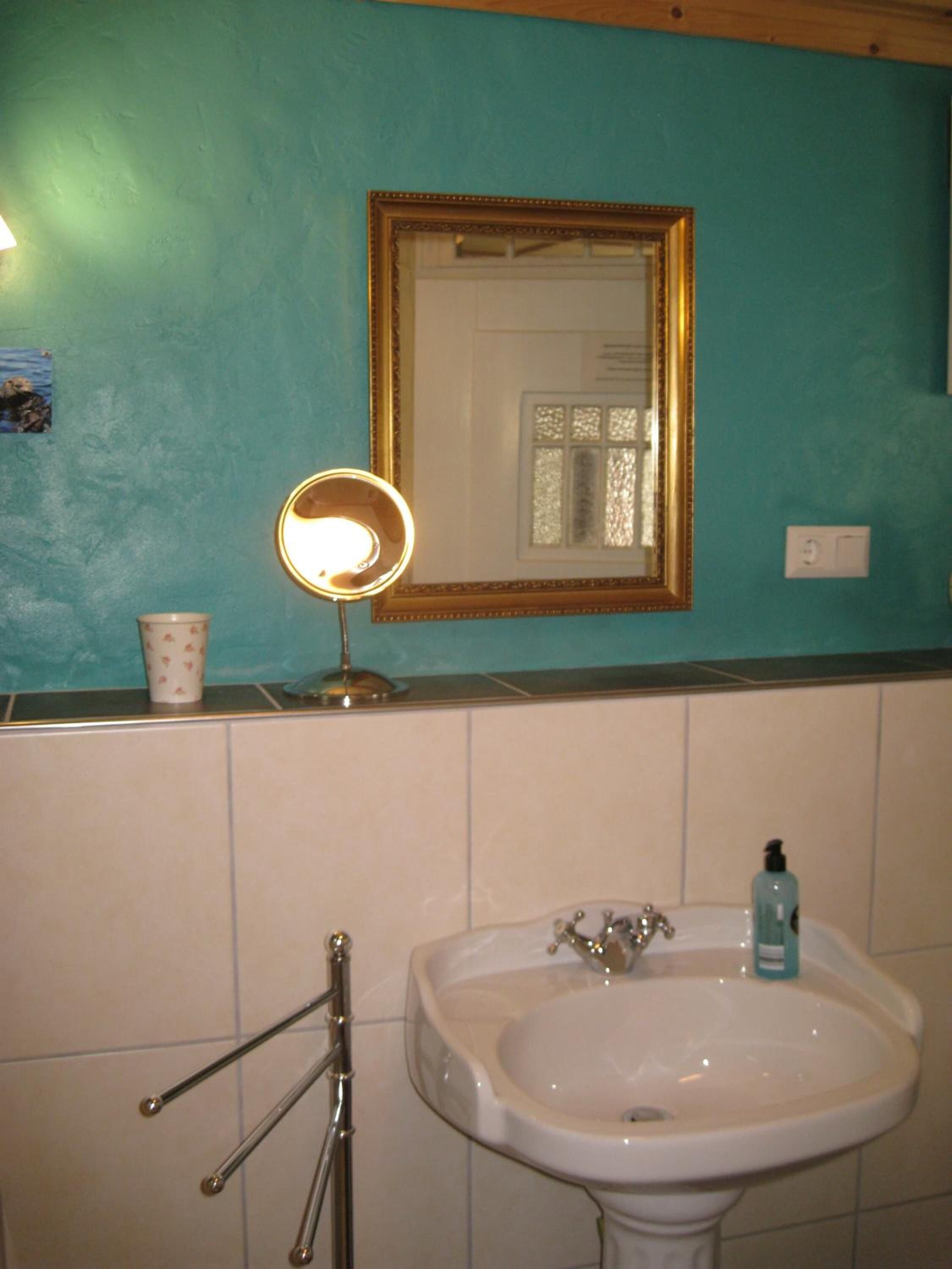 Ein Badezimmer mit Waschbecken, Spiegel und Handseife.