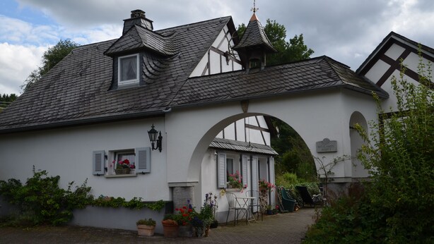 A traditional building with a white facade, a pitched roof, and a prominent archway. - Ferienhaus Romantikmühle Heartlandranch (Horbruch)
