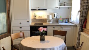 A kitchen with white cabinets, a coffee maker, and a kettle on the countertop. - Ferienhaus Romantikmühle Heartlandranch (Horbruch)