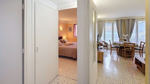 Une chambre d’hôtel comprenant un lit, un coin repas avec une table et des chaises, et offrant une vue sur l’extérieur grâce à de grandes fenêtres.