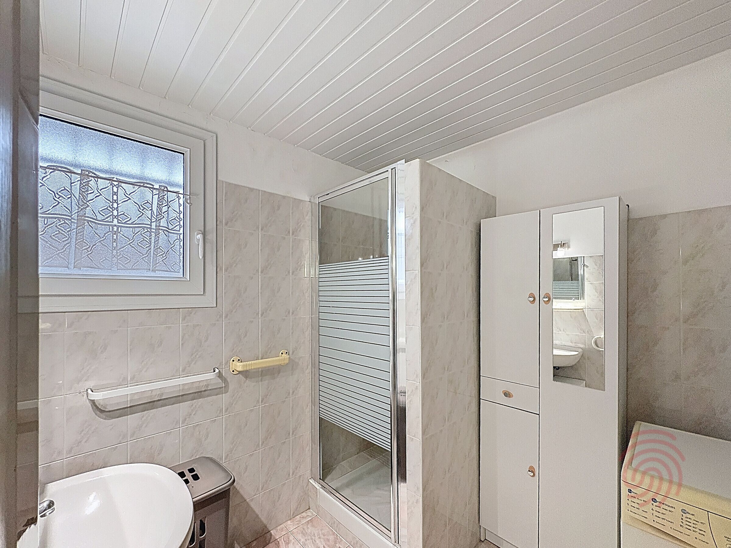 A bathroom with a toilet, a sink, a shower with a glass door, and a cabinet with a mirror.