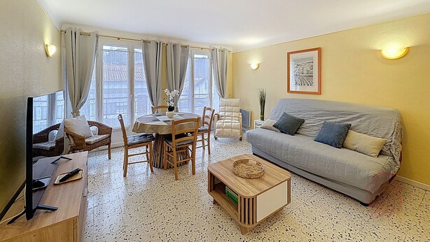 Un salon comprenant un canapé, une table à manger avec des chaises, un téléviseur et une table basse.