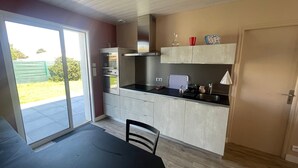 A compact kitchen with a built-in oven, a sink, and a dining area with a table and chairs.