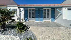 A two-story building with a tiled roof, a front entrance with glass doors, and a gravel driveway.