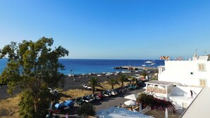 A coastal view with a marina, parked vehicles, and buildings with balconies overlooking the sea. - Case La Pergola (Santa Marina Salina)