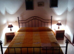 A single bed with a metal frame, two bedside tables with lamps, and a wall-mounted picture above the bed. - Case La Pergola (Santa Marina Salina)