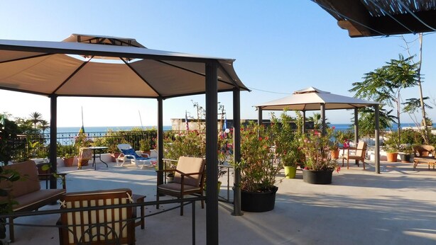 An outdoor patio area with seating arrangements, potted plants, and a view of the sea. - Case La Pergola (Santa Marina Salina)